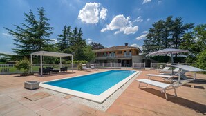 A rectangular swimming pool with a white border, surrounded by a patio area with lounge chairs and a pergola. - Nice home in Asti with jacuzzi (Asti)