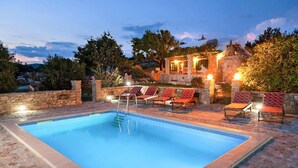 A swimming pool with stone tiles, surrounded by lounge chairs and a stone wall. - Pet friendly home in Selca (Selca)