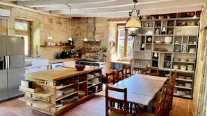 Una cocina rústica con una isla de madera, estanterías empotradas y un comedor con sillas.