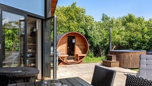 A modern outdoor seating area with a wooden deck, a hot tub, and a wooden barrel structure. - Amazing home in Sydals with sauna (Sydals)
