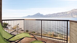 Ein Balkon mit Blick auf ruhiges Gewässer und Berge in der Ferne.