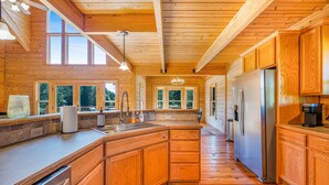 A spacious kitchen with wooden cabinets, a stainless steel refrigerator, and a large island with a sink.