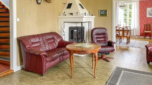 Un salon doté d’une cheminée, d’un canapé en cuir et d’un coin repas avec des chaises.