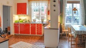 Une cuisine avec des meubles de rangement rouges, un évier et une fenêtre avec des rideaux.