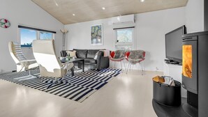 A modern living room with a sofa, chairs, a TV, and a fireplace. - Nice home in Skælskør with sauna (Skælskør)