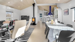 A modern living room with a fireplace, a dining area, and a kitchen. - Nice home in Skælskør with sauna (Skælskør)