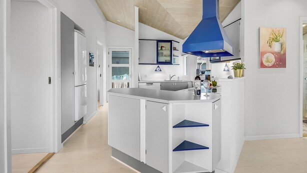 A modern kitchen with white cabinetry, a blue pendant light, and a central island with blue shelves. - Nice home in Skælskør with sauna (Skælskør)