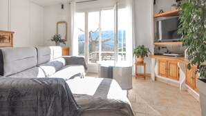 A modern living room with a sofa, a TV, and a view of the outdoors. - Amazing home in Salernes (Salernes)