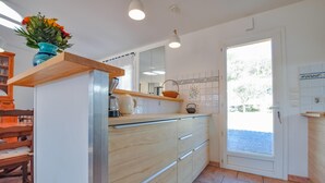 A modern kitchen with wooden cabinets, a built-in oven, and a large window. - Amazing home in Salernes (Salernes)