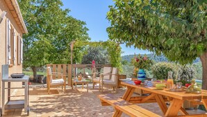 An outdoor patio with wooden furniture, including benches and chairs, and a table set with various items. - Amazing home in Salernes (Salernes)