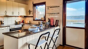 A kitchen with a central island, bar stools, a window with a view, and various kitchen appliances.