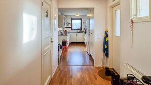 A narrow hallway with wooden flooring leading to a kitchen area.