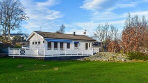 A single-story house with a covered porch, a fenced yard, and a large rock in the foreground.
