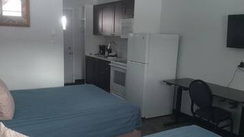 Una habitación con dos camas, una kitchenette y un escritorio con silla.