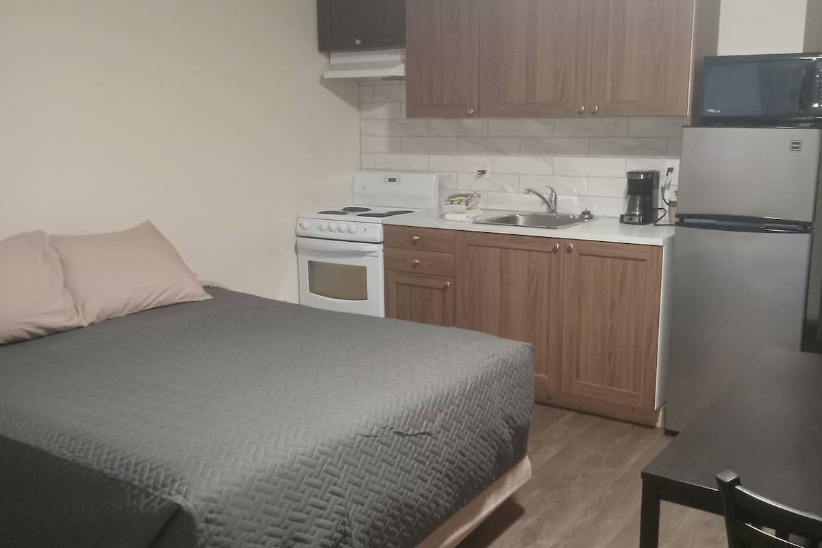 A compact kitchen with wooden cabinets, a stove, a microwave, and a refrigerator.