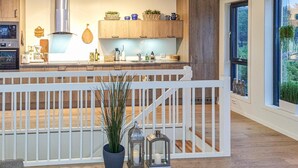 Una cocina moderna con armarios de madera, extractor de acero inoxidable y vistas al exterior a través de un ventanal grande.
