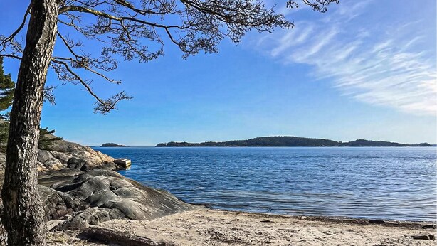 Una costa rocosa con cielo azul despejado y aguas tranquilas.