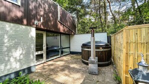 Une terrasse extérieure moderne, dotée d’un grand poêle à bois, d’un sol en briques et d’une clôture en bois.