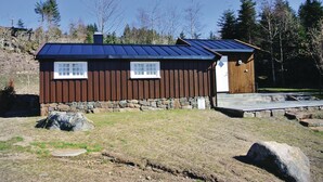 A cabin with a stone foundation, wooden siding, and a blue roof. - Awesome home in Farsund with house sea view (Farsund)