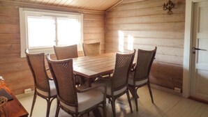 A wooden-paneled room with a wooden table and wicker chairs. - Awesome home in Farsund with house sea view (Farsund)