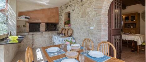 Un coin repas rustique avec un mur en pierre, une table en bois et des chaises.