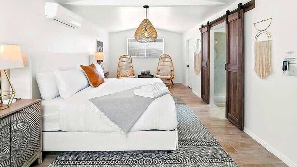 Een slaapkamer met een bed, nachtkastjes, een hanglamp en een schuifdeur.