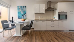 Una cocina moderna con gabinetes blancos, una campana extractora de acero inoxidable y un horno empotrado.