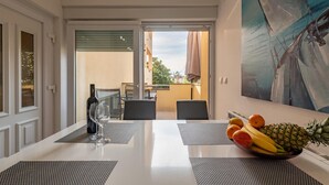 Un comedor con una mesa dispuesta para dos, una botella de vino y un bol de fruta.