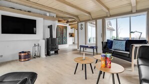 Een moderne woonkamer met een open haard, een bank, een salontafel en een aan de muur bevestigde televisie.