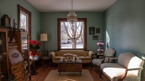 Una sala de estar acogedora con un sofá, sillones, una mesa de centro de madera y una araña.