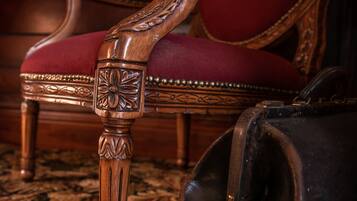 A wooden chair with intricate carvings and a red upholstered seat.
