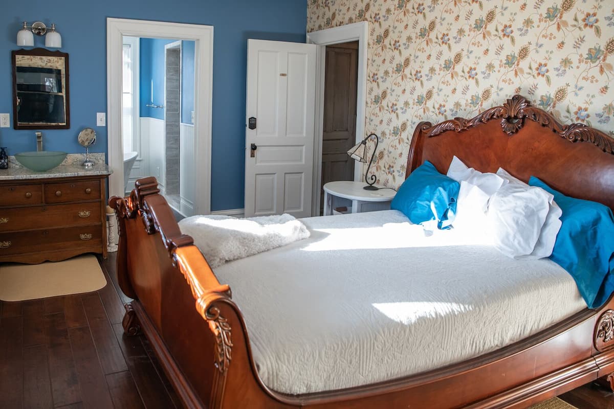 Une chambre à coucher avec un lit en bois, une commode, une coiffeuse et un miroir.