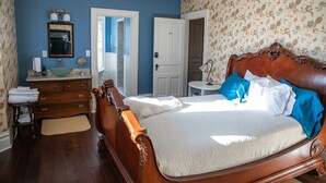 Un dormitorio con una cama de madera, un aparador, una tocador y un espejo.