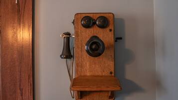Een houten telefoon bevestigd aan een wand in een kamer met houten lambrisering.