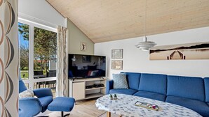 A living room with a TV, blue sofa, and a table with decorative items.