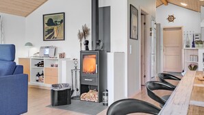 A modern living room with a fireplace, a sofa, a dining table, and a kitchen area.