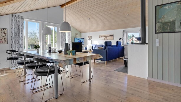 A modern kitchen with a wooden island, bar stools, and pendant lighting.