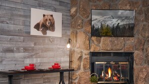 Una habitación acogedora con una chimenea de piedra, una mesa con tazas rojas y un cuadro de un oso en la pared.