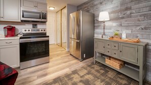 Una cocina moderna con electrodomésticos de acero inoxidable, una pared de madera y un armario con cajones.