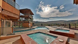 Un área de piscina con varias piscinas y un edificio de madera con balcones.
