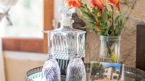 A tray with a glass decanter and two crystal glasses, a vase with orange flowers, and a small card with a house image. - "Tilleul" Room – Indulge in understated B&B luxury (Fayence)