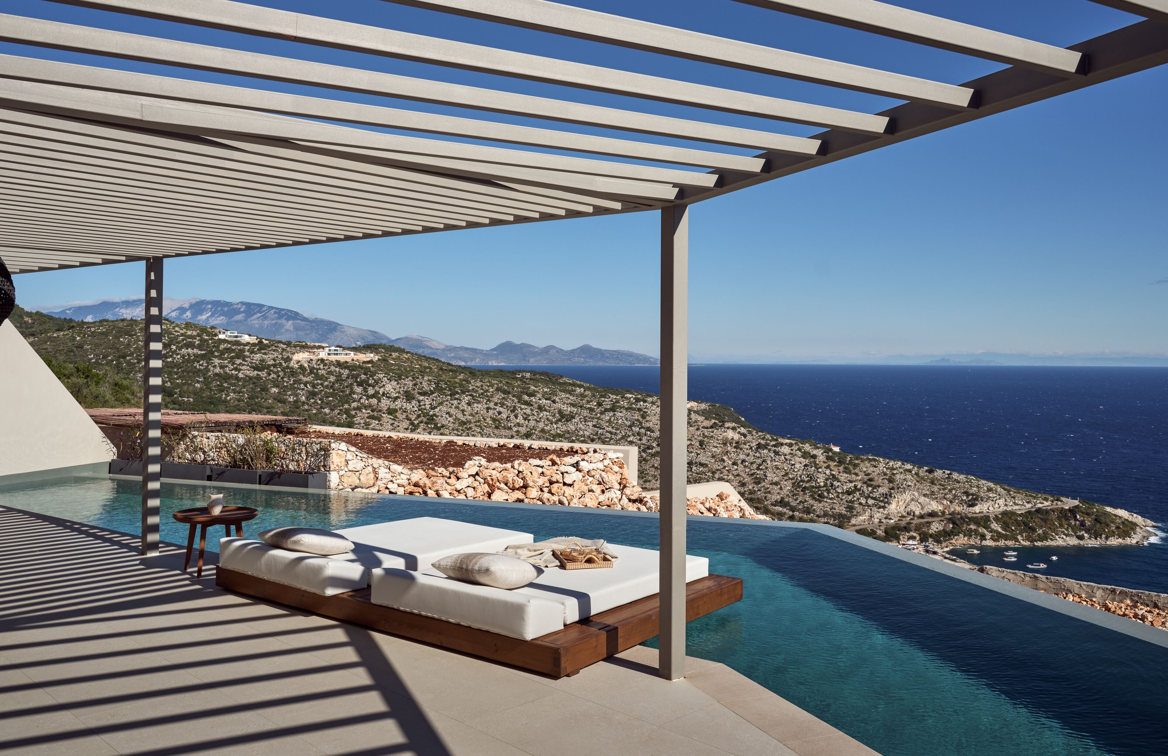 Una piscina a sfioro moderna con vista sul mare e sulle montagne.