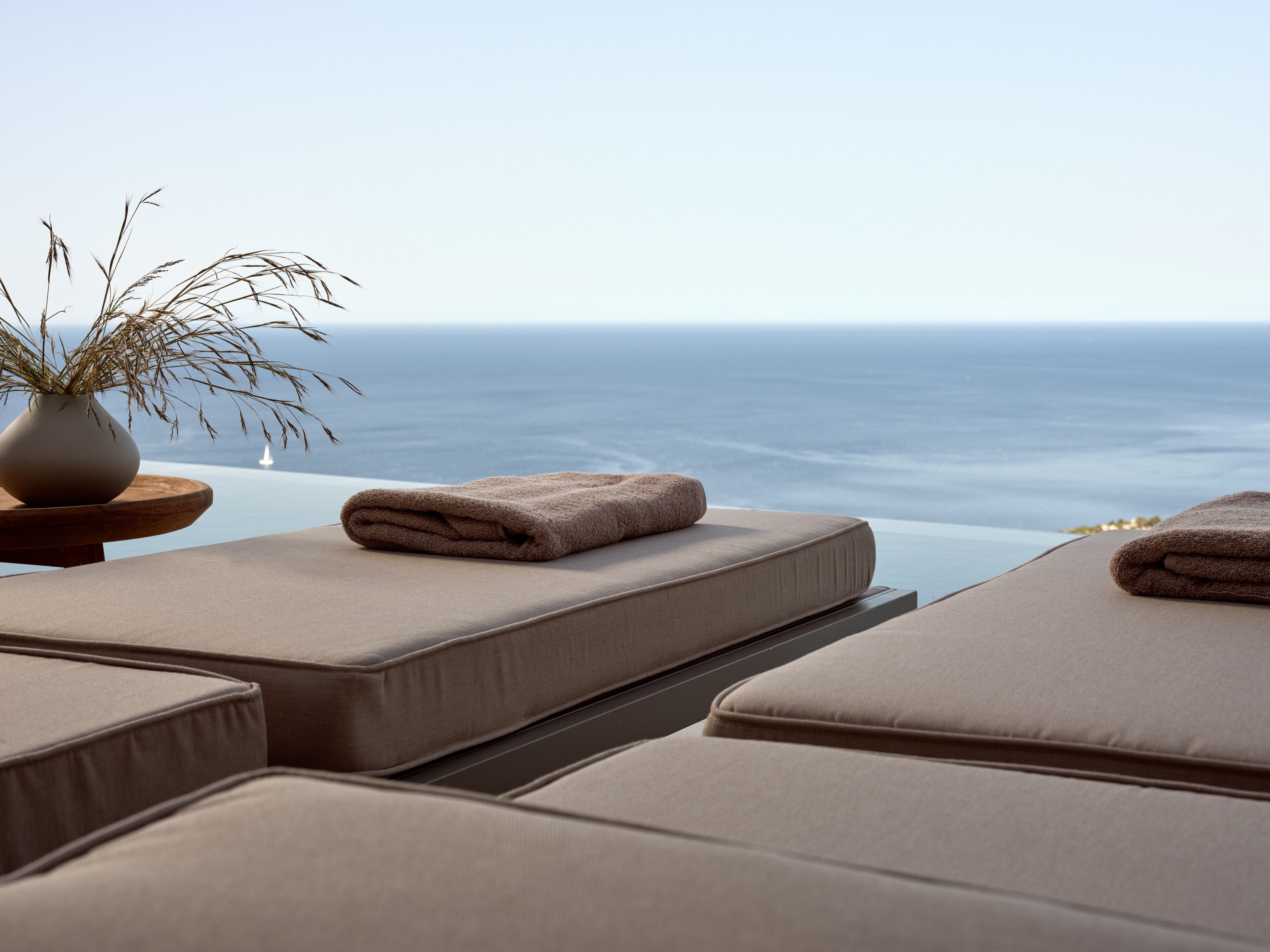 A seaside view with lounge chairs and a vase of dried plants.