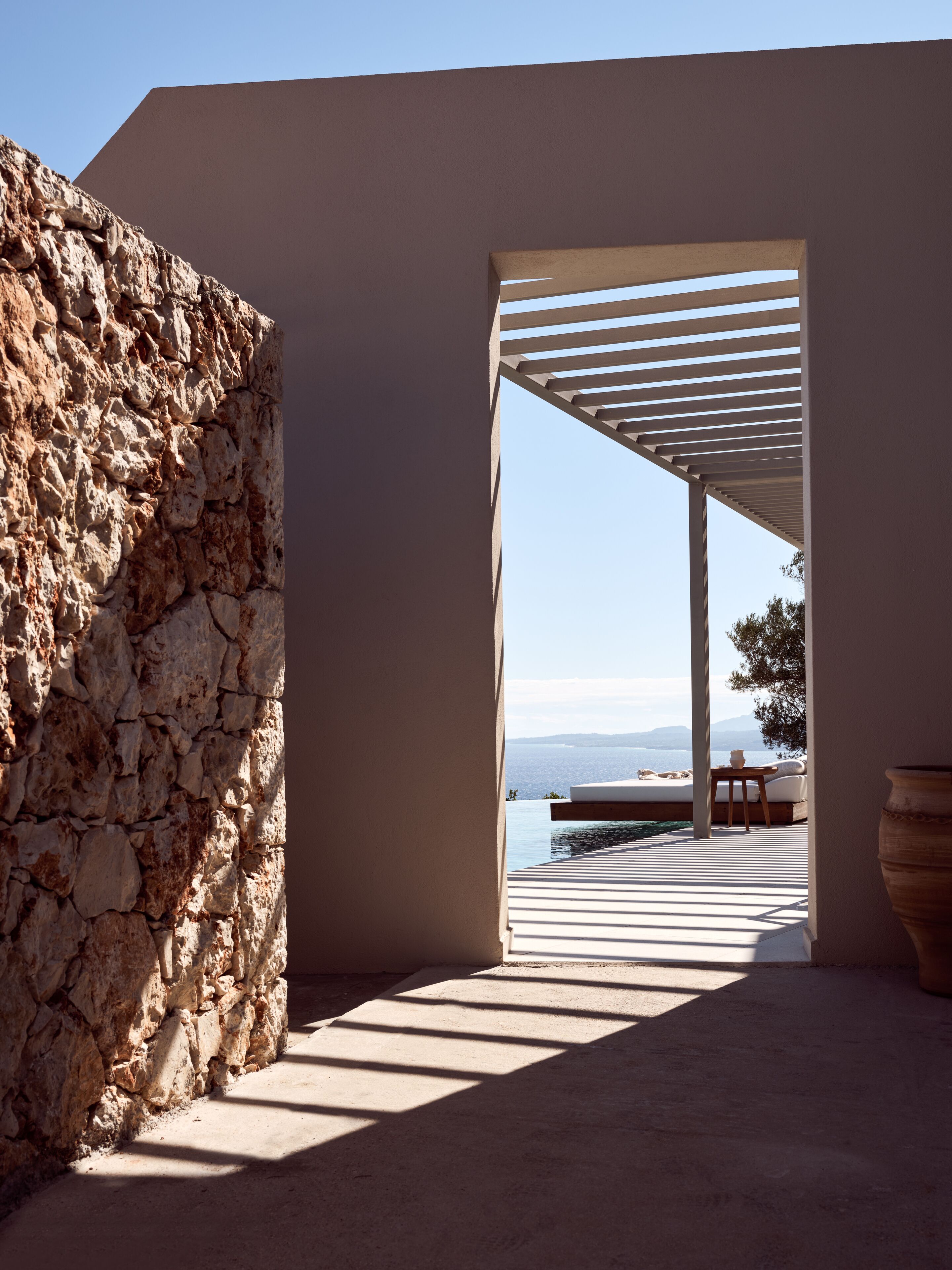 A stone wall and a covered outdoor area with a view of the sea.