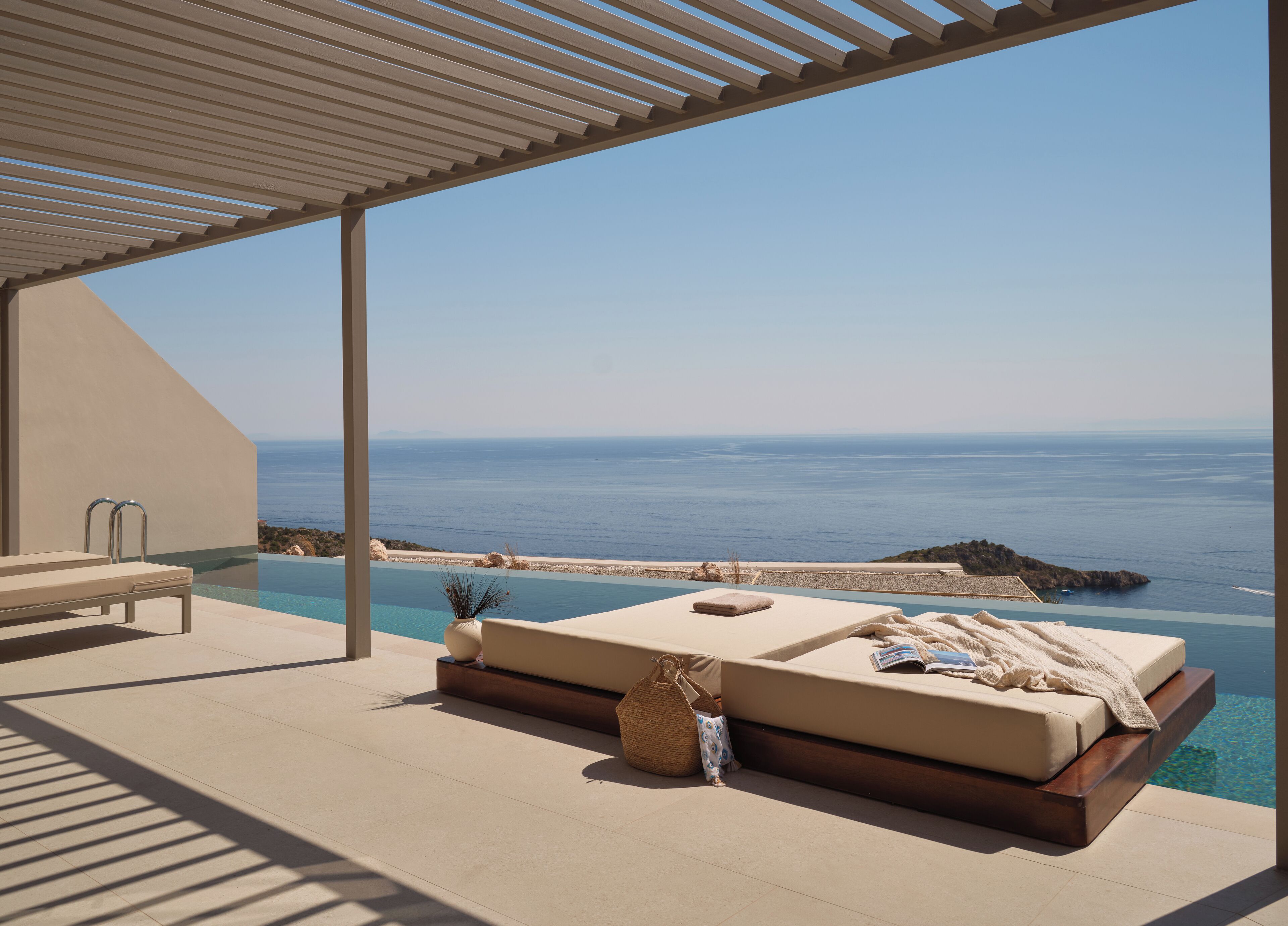 Ein sonniger Außenbereich mit Liegebereich, Pool und freiem Blick auf das Meer.