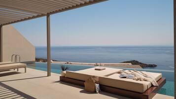 Ein sonniger Außenbereich mit Liegebereich, Pool und freiem Blick auf das Meer.