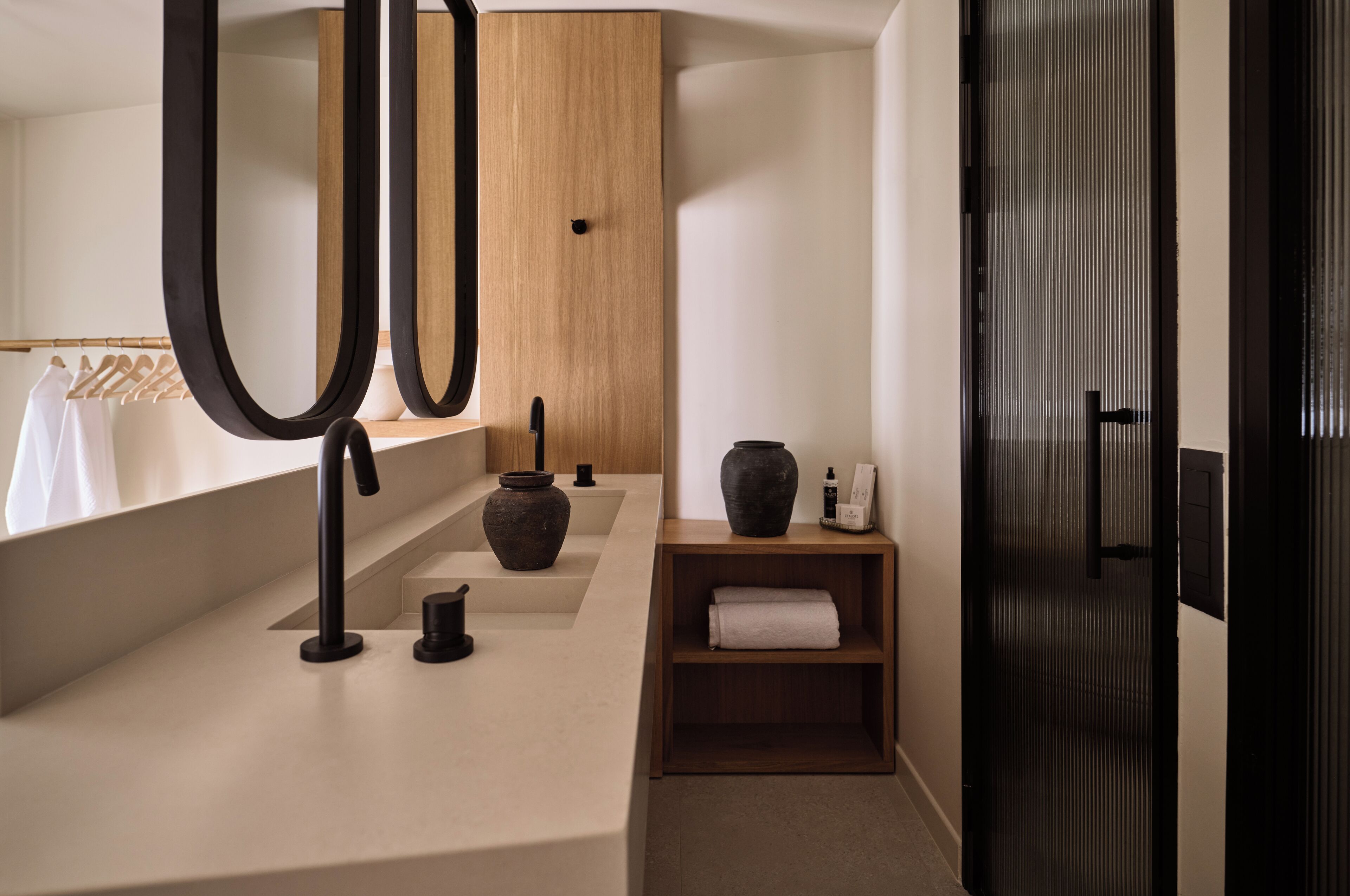 Une salle de bain moderne avec un meuble-lavabo en bois, un grand miroir et une porte noire.