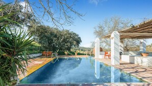 A swimming pool with a tiled deck, surrounded by greenery and trees. - Pet friendly home in Valverde de Leganés (Valverde de Leganés)