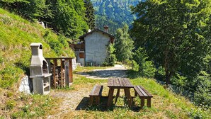 A rustic mountain cabin with a stone chimney, a wooden bench, and a picnic table. - 2 bedroom nice home in Sovramonte (Sovramonte)