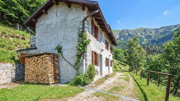 A rustic mountain house with a stone wall, wooden shutters, and a clear view of the surrounding mountains. - 2 bedroom nice home in Sovramonte (Sovramonte)